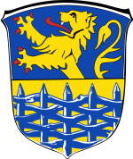 Wappen Samtgemeinde Hage In diesem Bild sehen Sie das Wappen der Samtgemeinde Hage. Der Hintergrund ist hellblau und gelb. Im Vordergrund ist ein hellblauer Zaun zu sehen. Hinter dem Zaun befindet sich ein gelber Löwe.